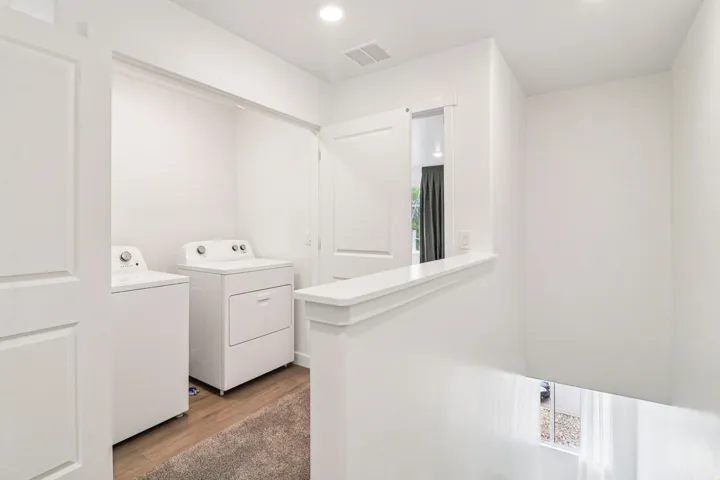 Dedicated laundry area featuring a washer and dryer, wood-finish flooring, and recessed ceiling lighting