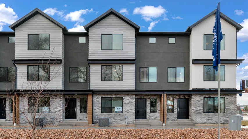 Contemporary townhome facade featuring a blend of light gray siding, dark gray stucco, and a gray brick-finish lower level