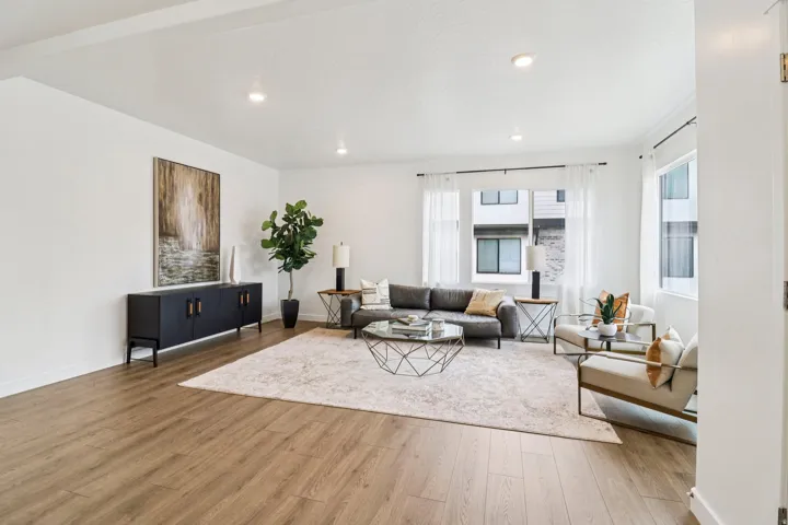 Spacious living area featuring recessed lighting, wood-finish flooring, and multiple windows