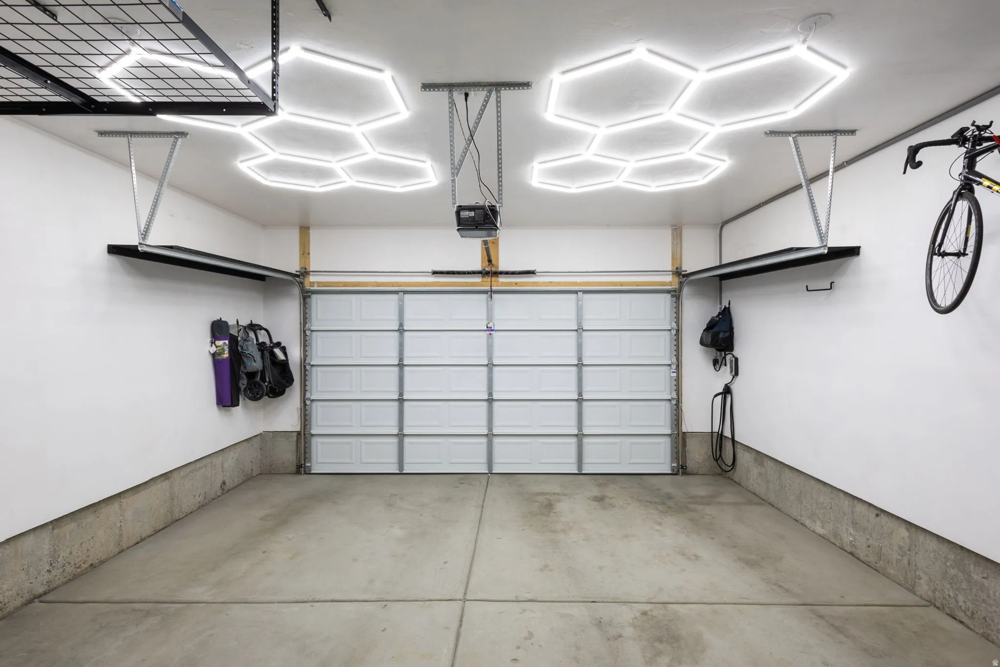 Spacious garage with a sectional overhead door, concrete flooring, and hexagonal ceiling light fixtures