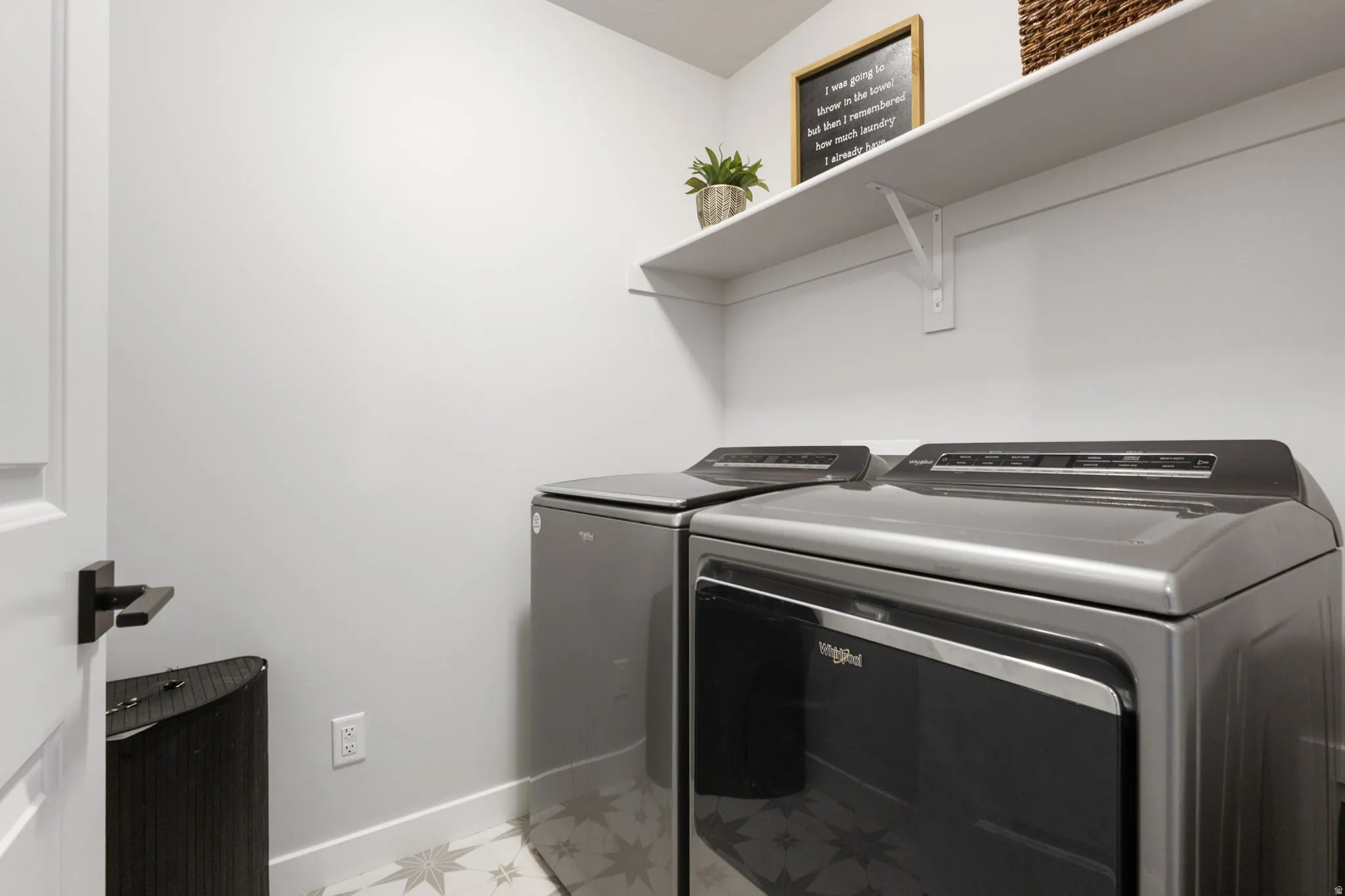 Dedicated utility space featuring patterned floor tile and a contrasting white baseboard