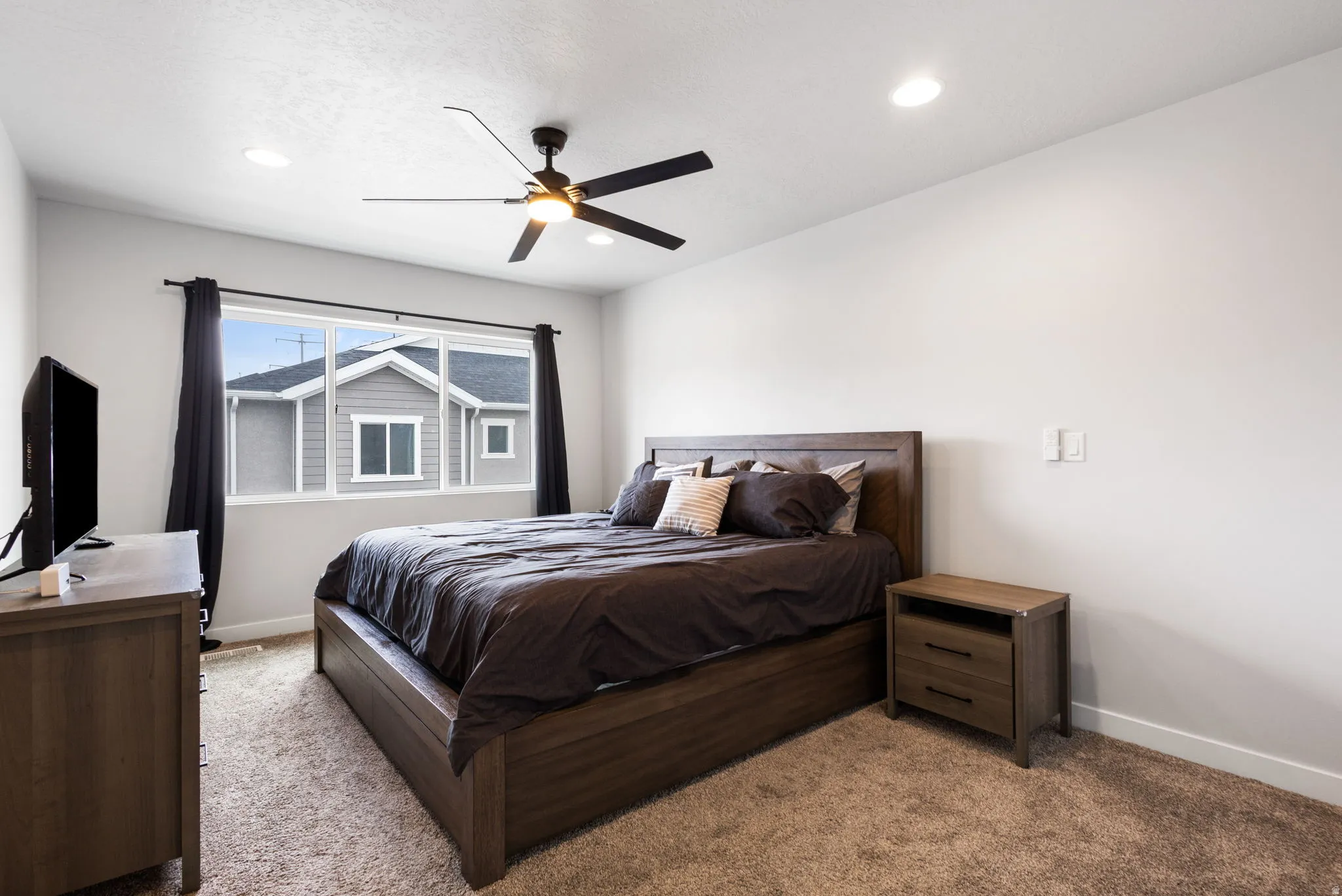 Spacious bedroom featuring light-colored walls, recessed lighting, and a contemporary ceiling fan