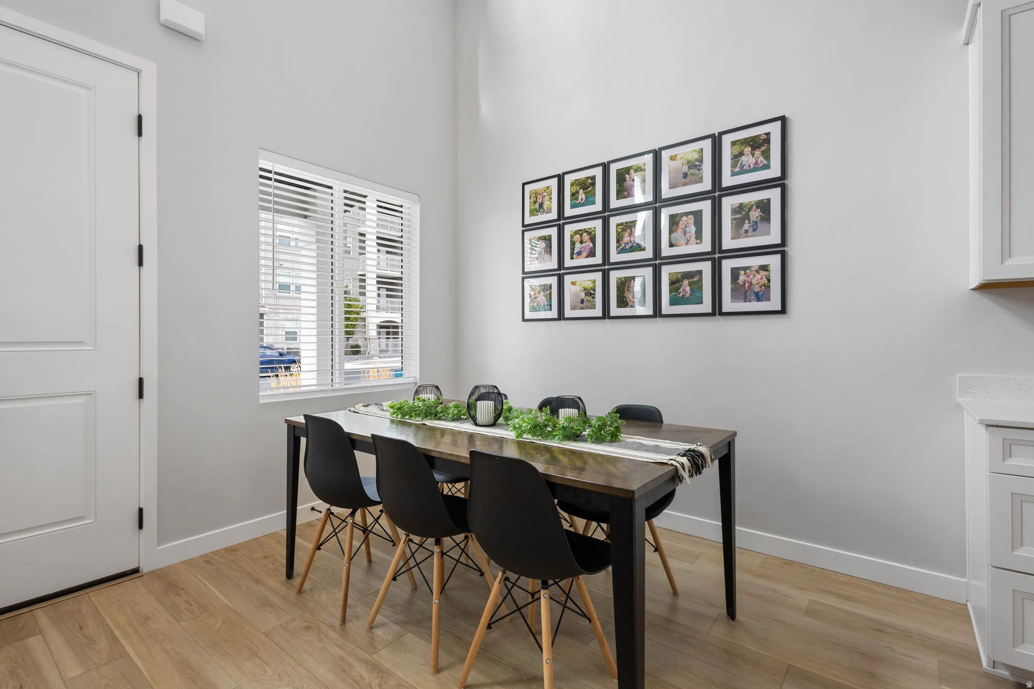 Dining area featuring light wood-finish flooring, a white paneled door, and a window with blinds