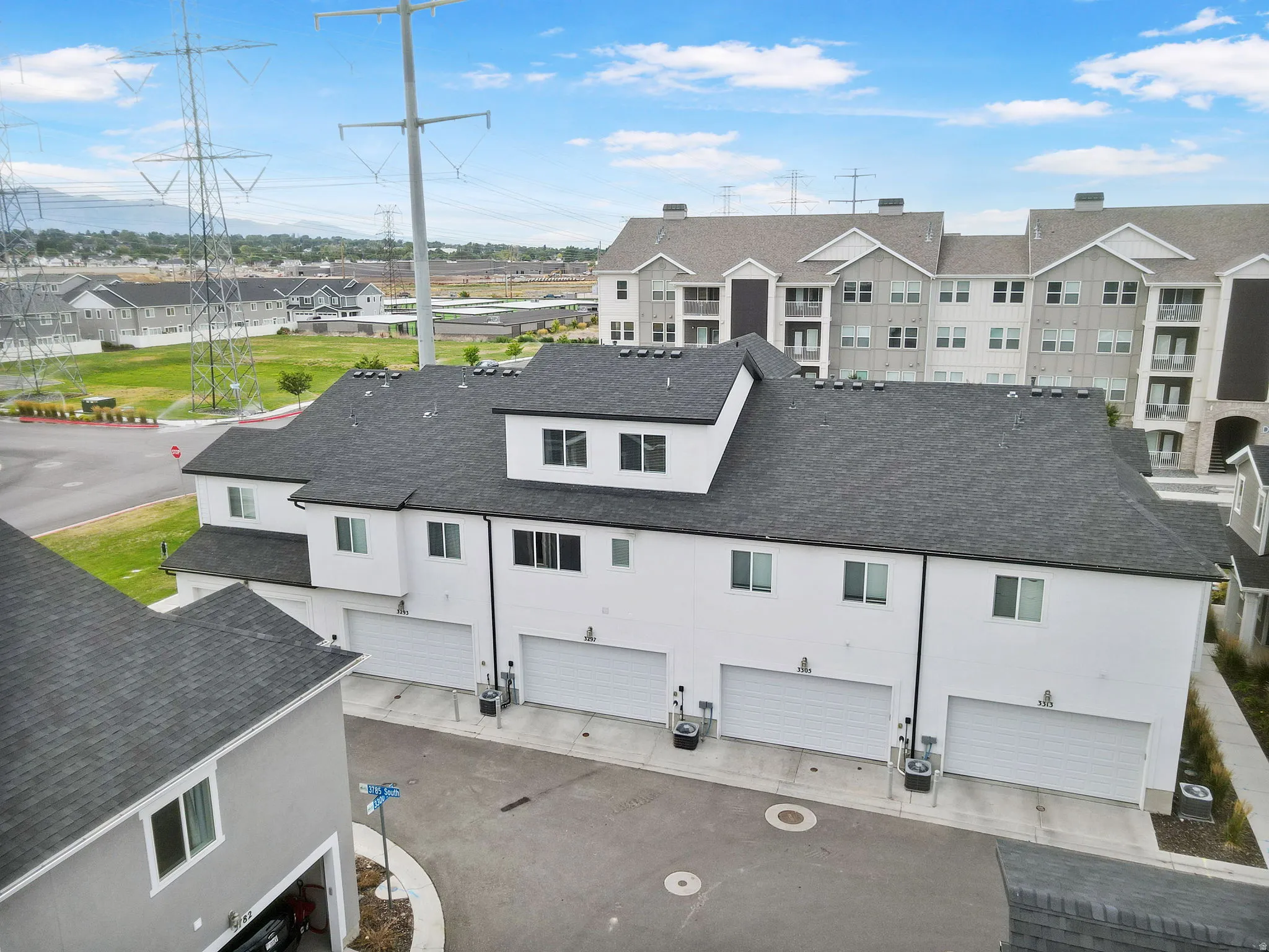 Townhome-style residences featuring a multi-car garage, white facade, and dark roofline