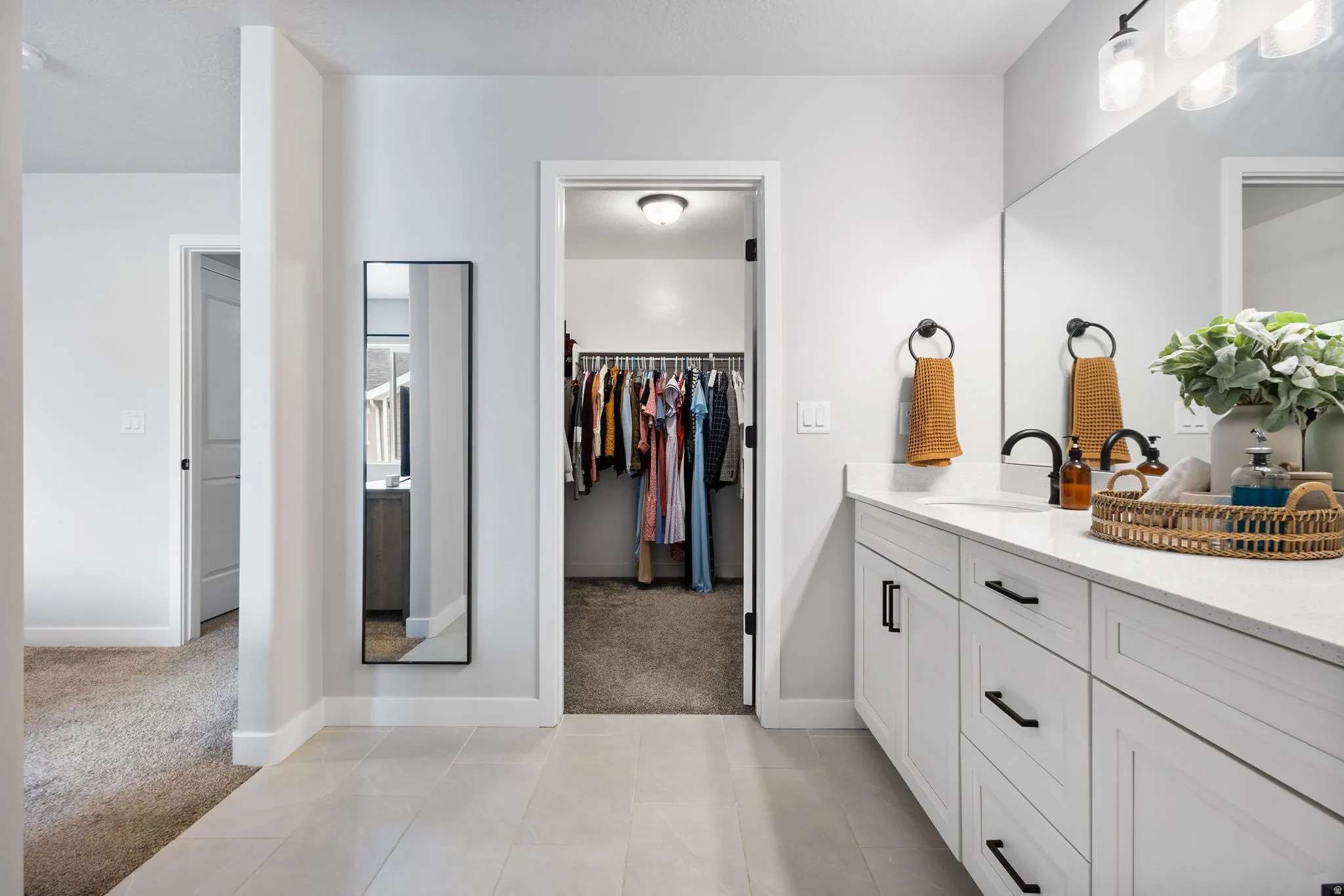 Dual-sink vanity with white cabinetry, quartz countertop, and black hardware