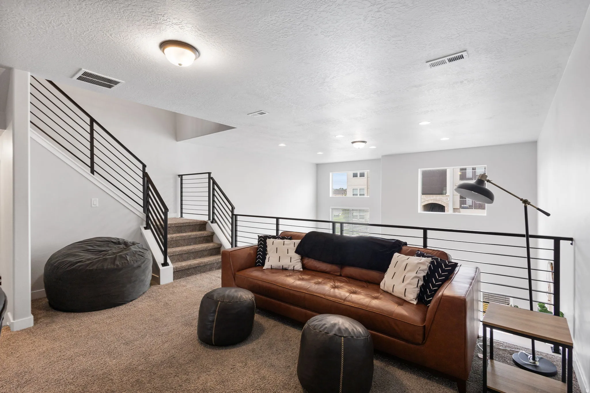 Loft area featuring neutral carpeting, contemporary horizontal bar railings, recessed lighting, and a drum light fixture