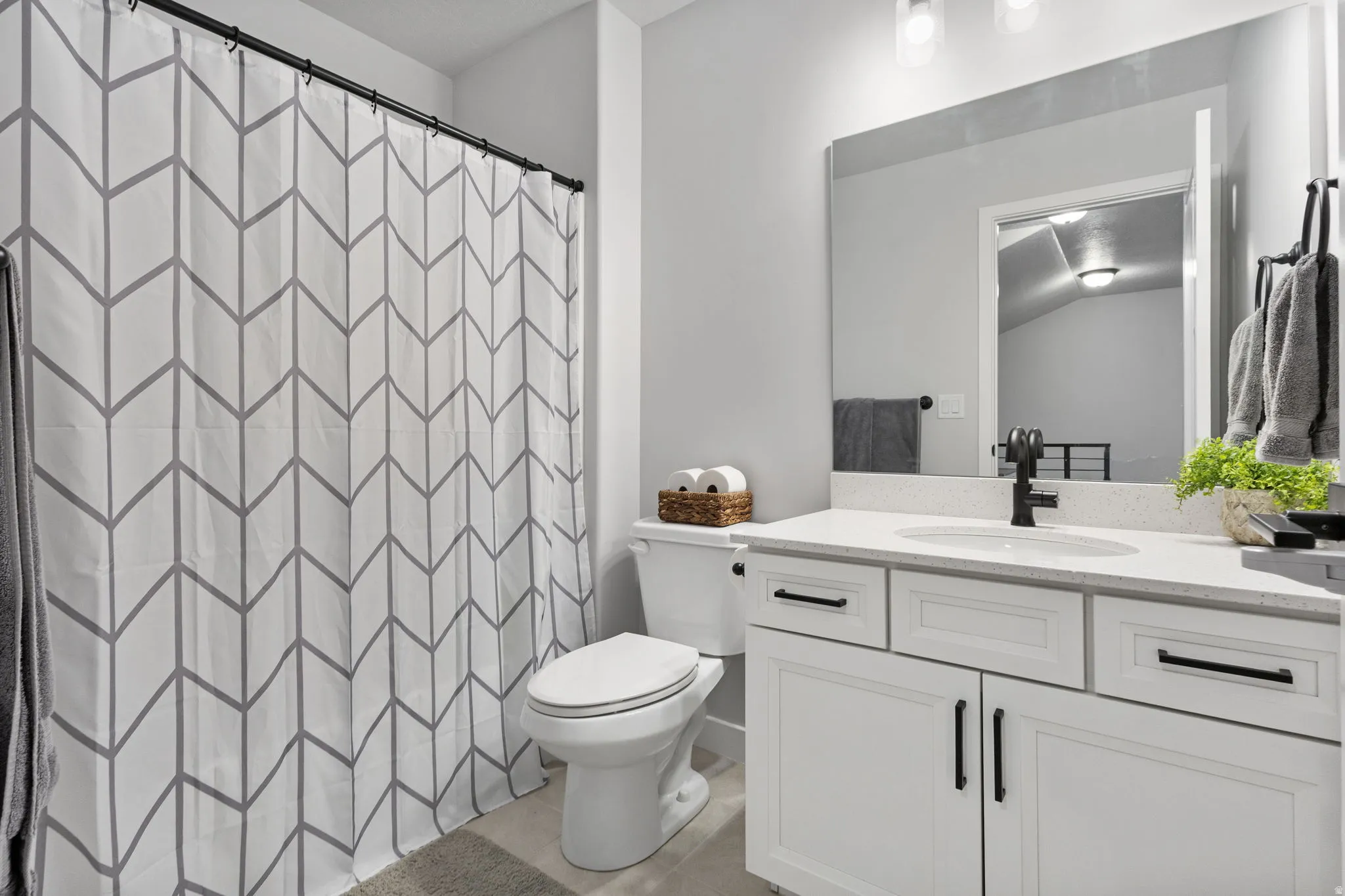 Bathroom vanity featuring a solid surface countertop, undermount sink, and matte black hardware