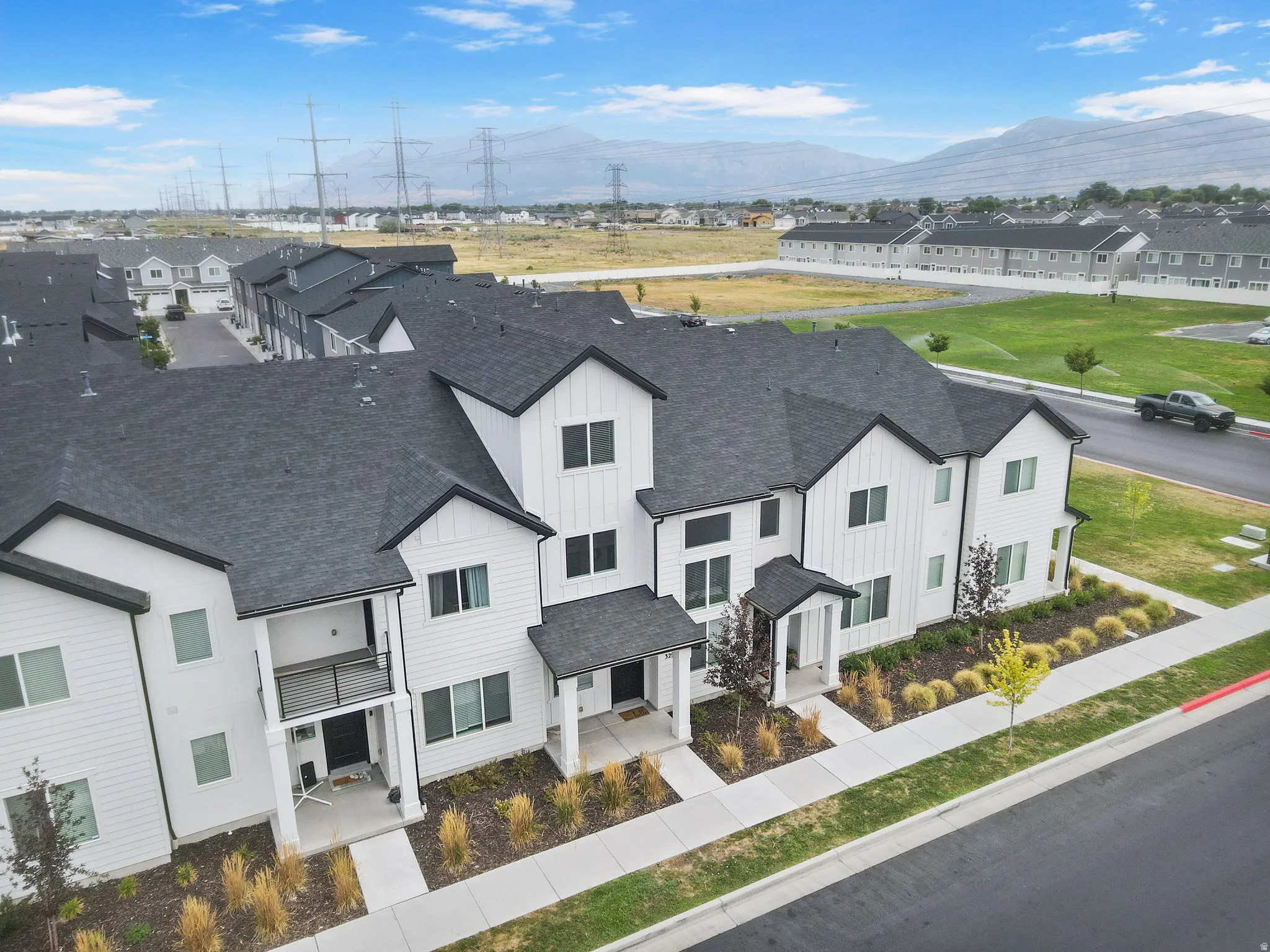 Modern townhome exterior featuring white siding and dark shingled roofs