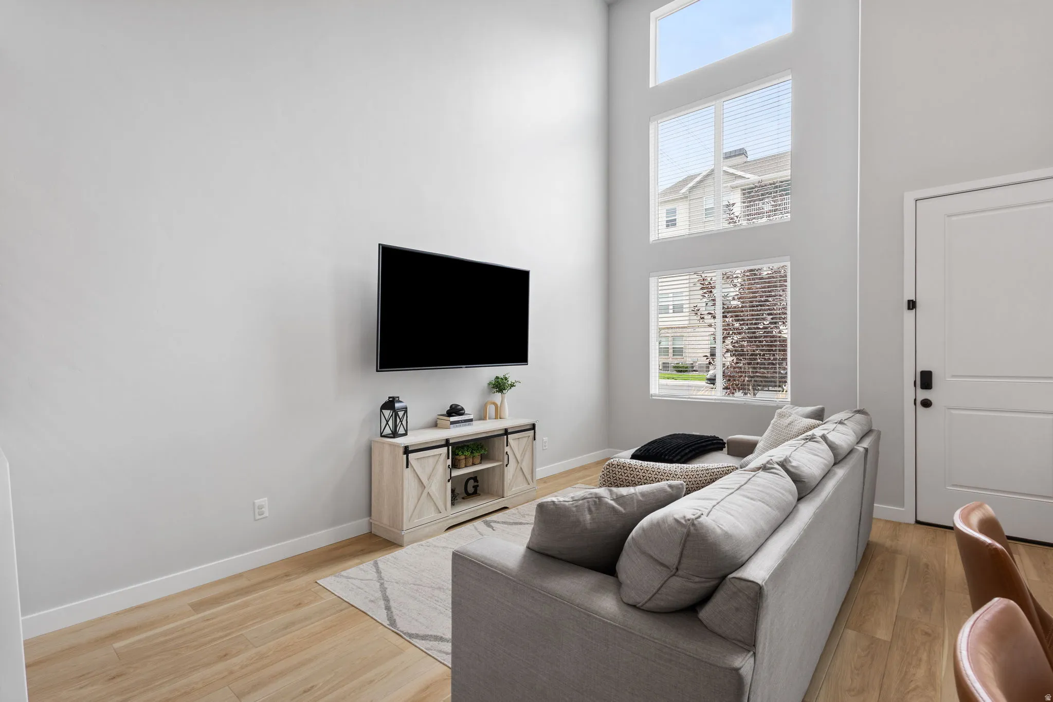 Living area featuring a soaring ceiling, wood-finish flooring, and a multi-level window arrangement