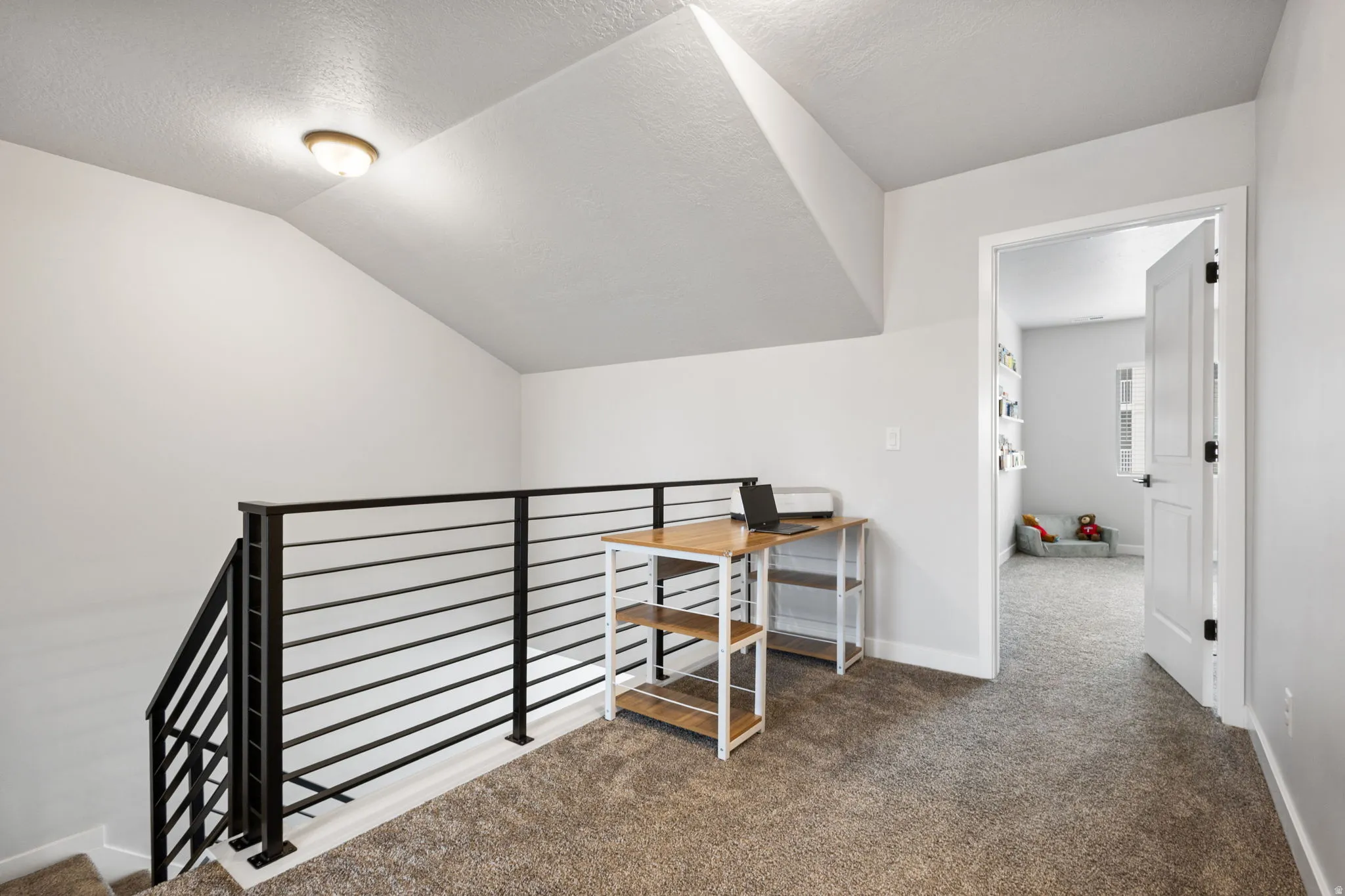 Carpeted loft area featuring a contemporary horizontal black metal railing overlooking the staircase