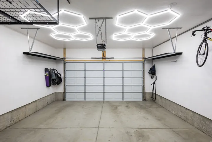 Spacious garage with a sectional overhead door, concrete flooring, and hexagonal ceiling light fixtures