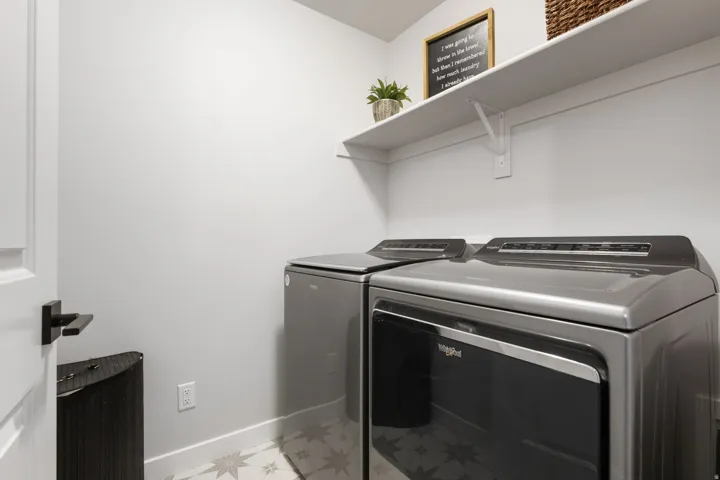 Dedicated utility space featuring patterned floor tile and a contrasting white baseboard