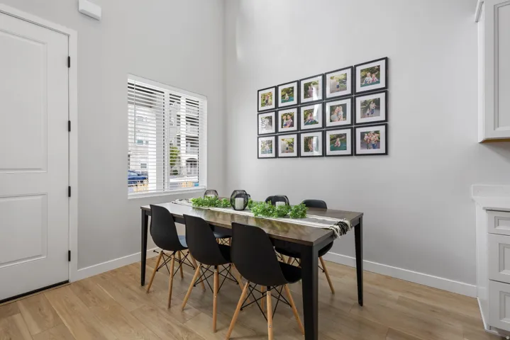 Dining area featuring light wood-finish flooring, a white paneled door, and a window with blinds