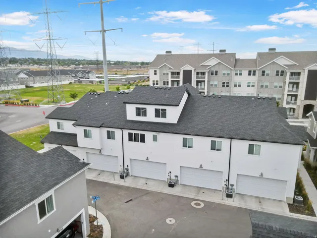 Townhome-style residences featuring a multi-car garage, white facade, and dark roofline