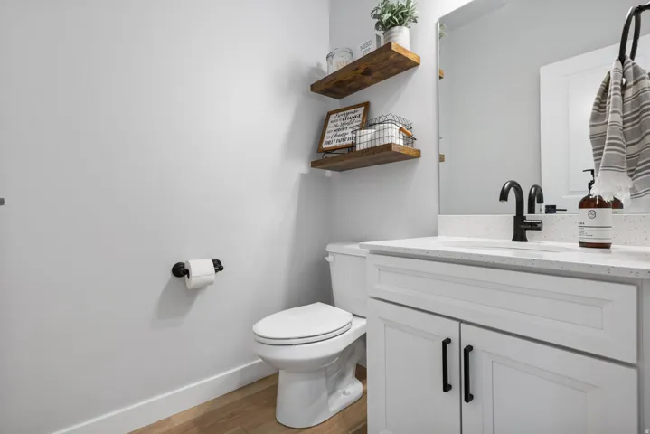 Bathroom vanity with white cabinetry, a speckled countertop, and a black gooseneck faucet
