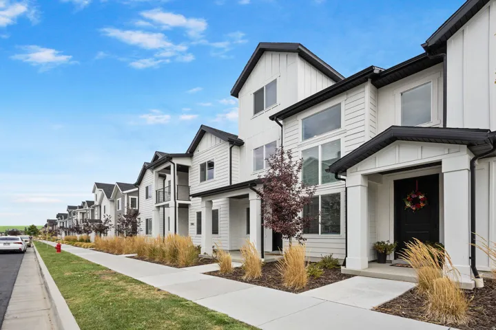 Modern townhome exterior featuring white board and batten siding, black trim, and a covered entry