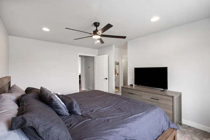 Bedroom featuring a wood-finish bed frame, carpet flooring, and a contemporary ceiling fan