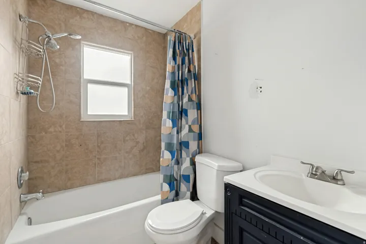 Bathroom featuring a white bathtub, tiled shower surround, and a window