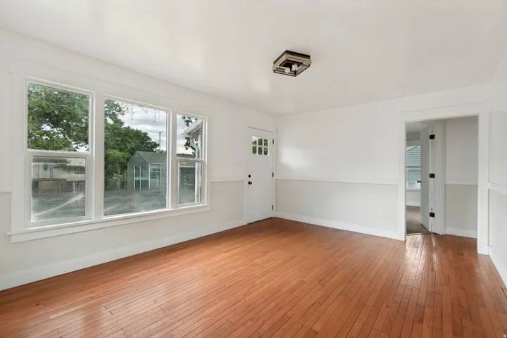 Bright interior space featuring wood-finish flooring, white walls with wainscoting, and large multi-pane windows