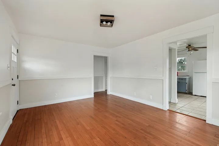 Warm-toned wood-finish flooring extends throughout this room, complemented by white walls and a white chair rail molding