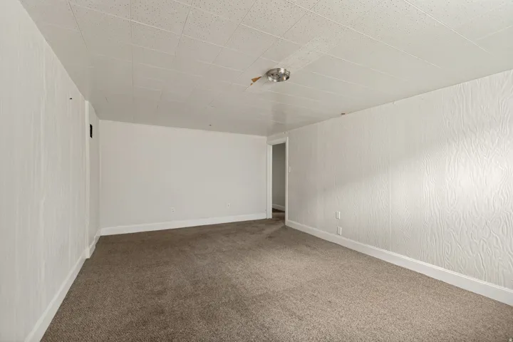 Carpeted room with a textured ceiling, white baseboards, and a flush-mount ceiling light