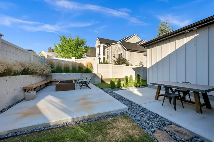 Outdoor patio featuring concrete slab construction, integrated wood-finish bench seating, a built-in fire pit, and a separate dining area with a concrete-top table