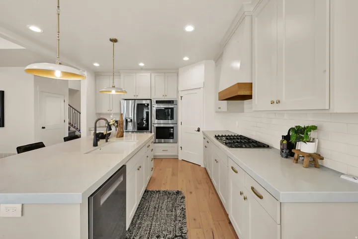 Modern kitchen featuring light-toned cabinetry, stainless steel appliances, and wood-finish flooring