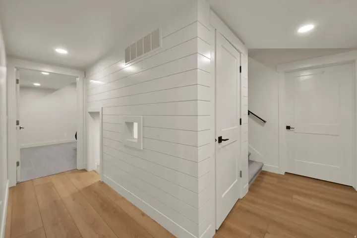 Hallway featuring wood-finish flooring, recessed lighting, and white shiplap wall paneling
