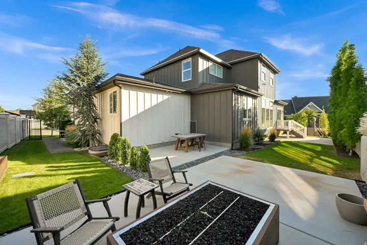 Contemporary exterior featuring board and batten siding, multiple windows, and a paved patio area
