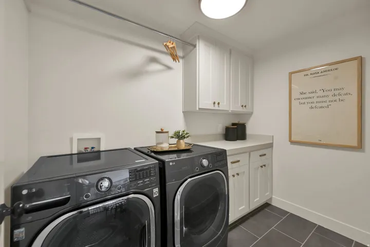 Laundry area featuring white cabinetry, a light-toned countertop, and dark rectangular floor tiles