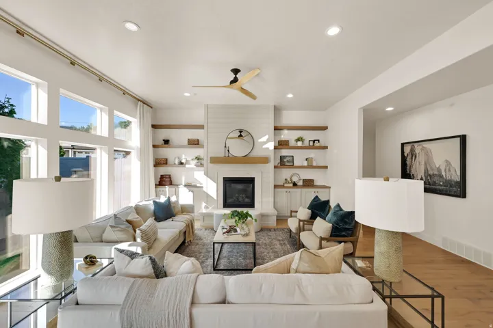 Bright living space featuring a shiplap-clad fireplace with a wood mantel, built-in cabinetry, and integrated shelving