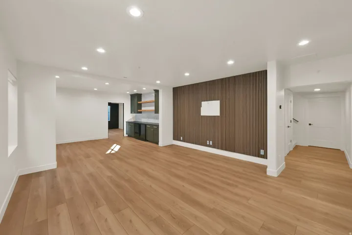 Spacious interior featuring wood-finish flooring, recessed lighting, and a contemporary accent wall