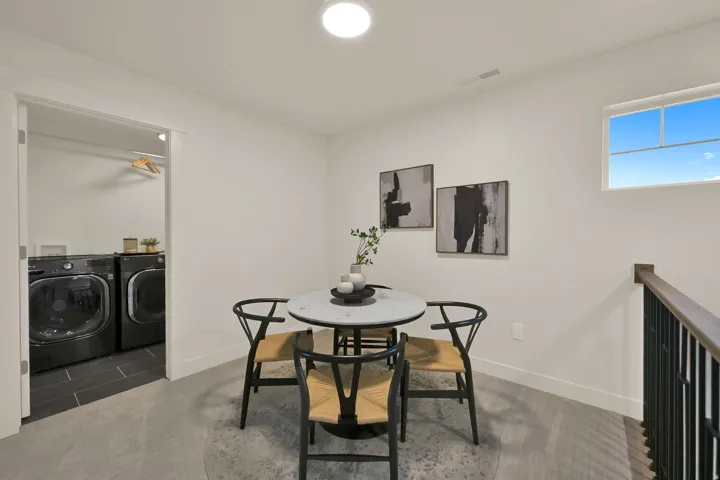 Upper-level landing featuring a laundry area with dark tile flooring, a built-in closet rod, and an overhead light fixture