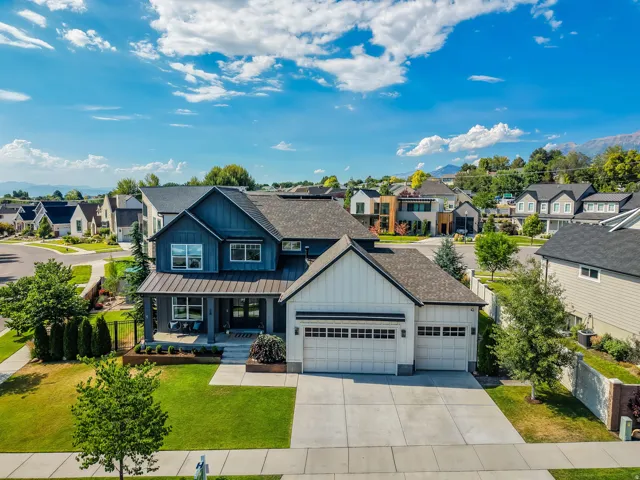 Contemporary residence featuring a dark blue facade with white accents, a covered front porch, and a three-car garage