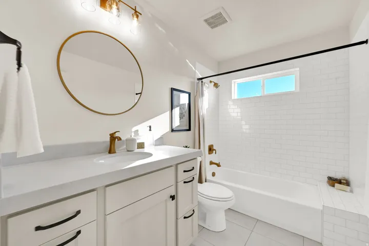 Bathroom featuring a white subway tile shower surround, a built-in tub, and a vanity with a white countertop