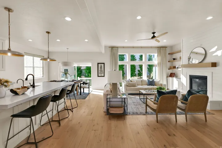 Open-concept living space featuring wood-finish flooring, a contemporary fireplace with shiplap surround, and an expansive window wall