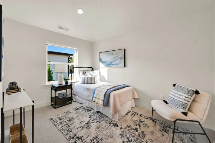 Bedroom featuring light-toned wood-finish flooring and a single window with exterior landscaping visible