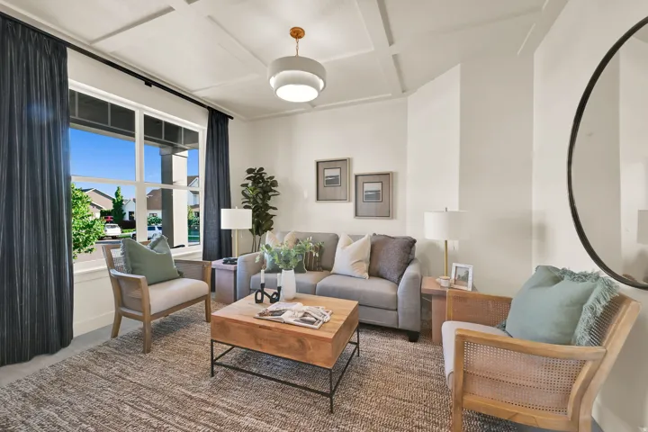 Living area featuring a coffered ceiling with a modern pendant light, large multi-pane window, and light-toned wall finishes