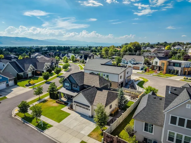 Aerial perspective of a modern residential neighborhood featuring established landscaping, paved streets, and a distant mountain range backdrop