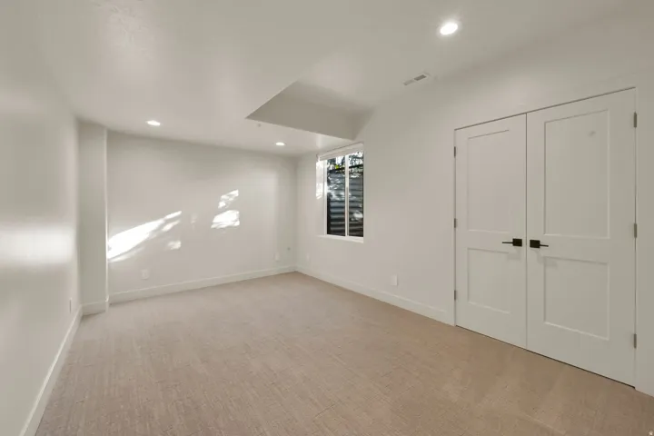Spacious room featuring neutral carpeting, a large egress window, and recessed ceiling lighting