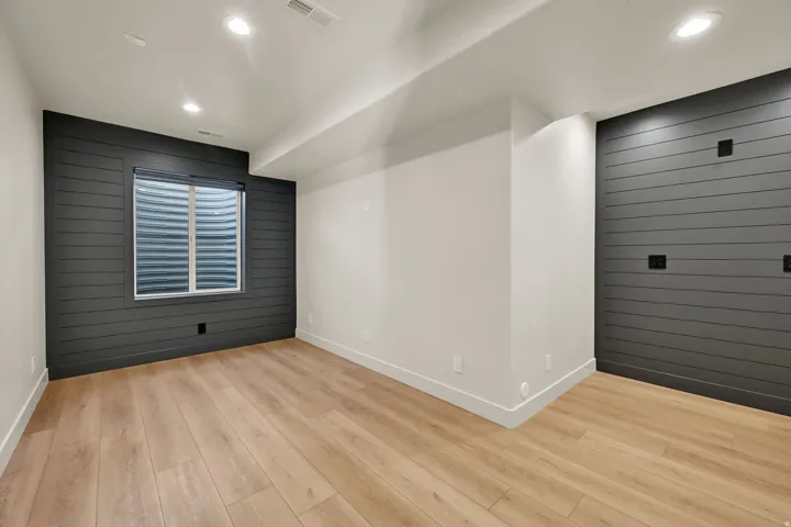 Spacious room featuring light wood-finish flooring, recessed lighting, and a window with blinds