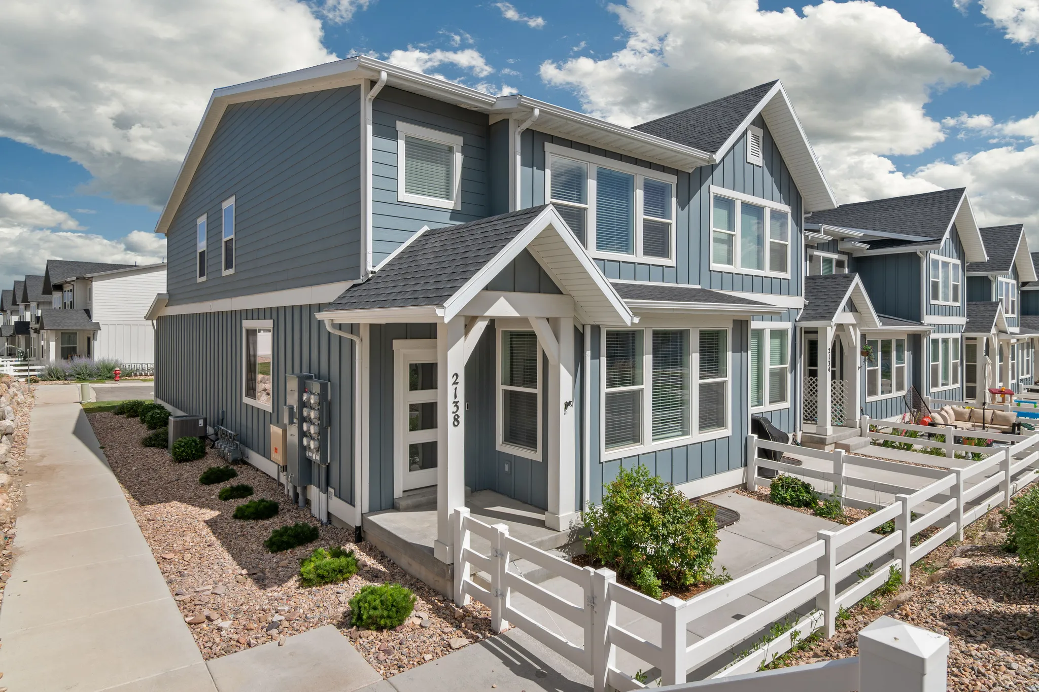 Modern townhome exterior featuring blue vertical siding with white trim