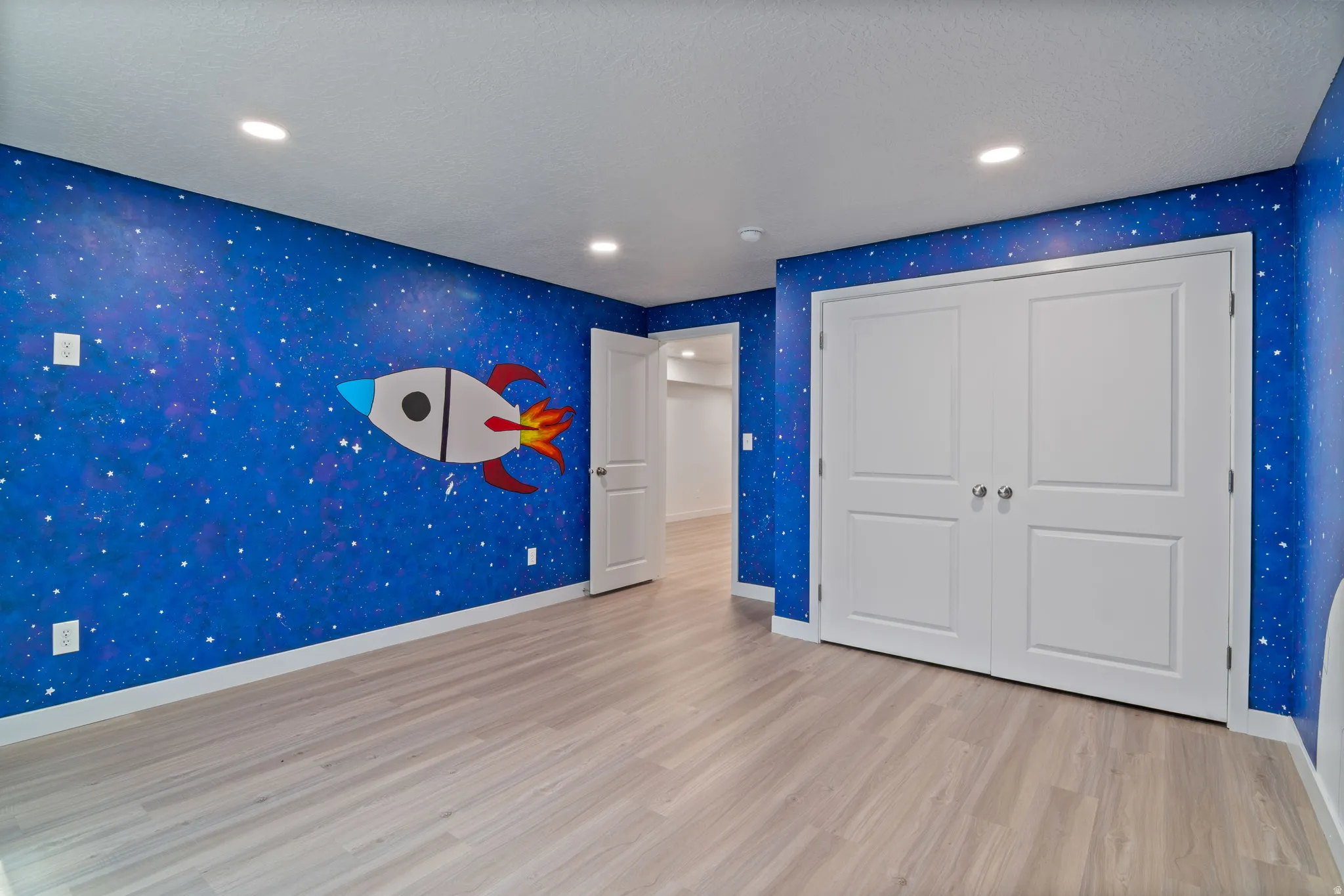 Large Bedroom featuring a vibrant space-themed mural, wood-finish flooring, a window, recessed ceiling lighting, and white baseboards