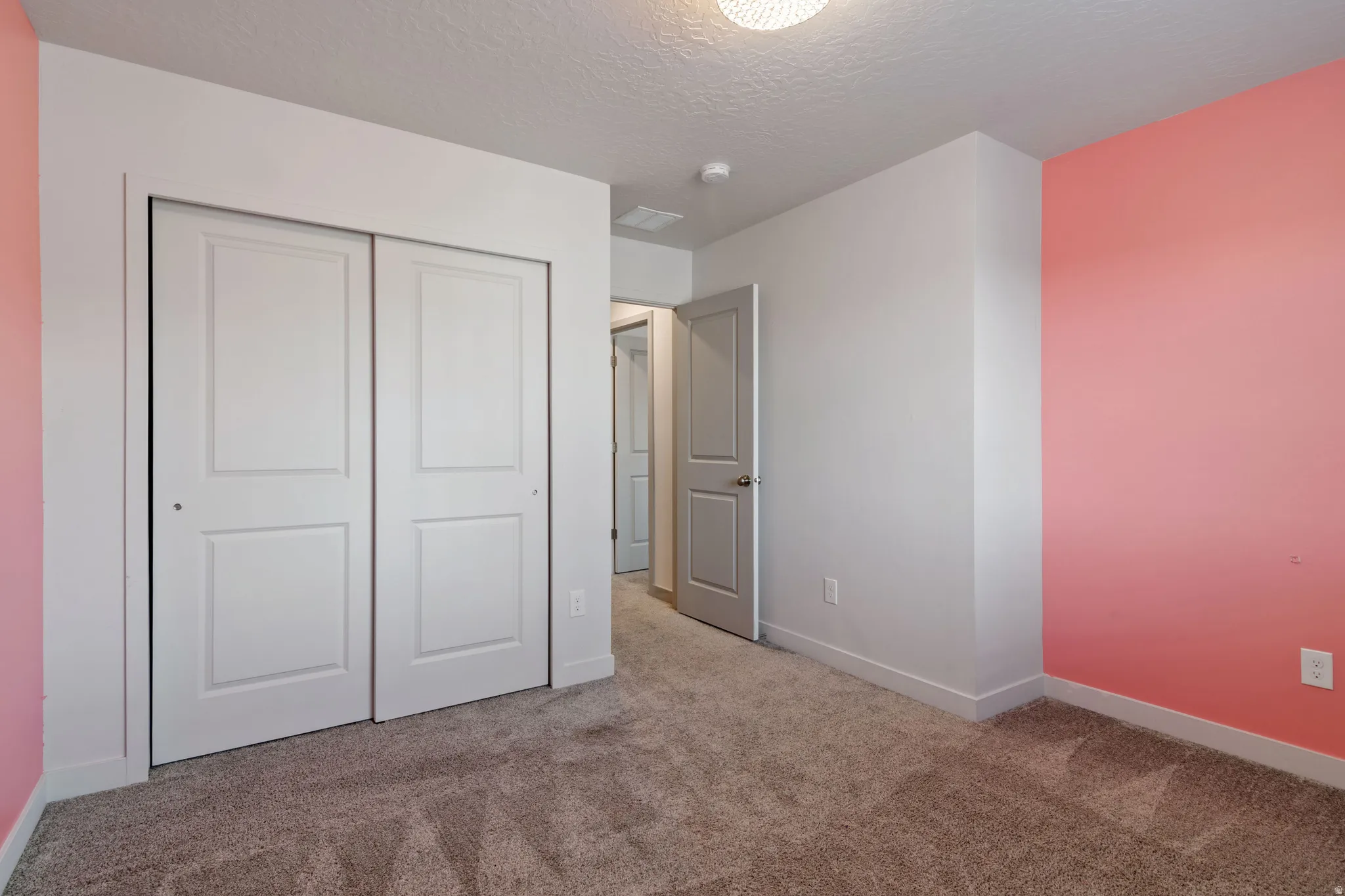 Bedroom featuring a two-panel sliding closet, neutral carpet, and a light-colored wall palette with an accent wall