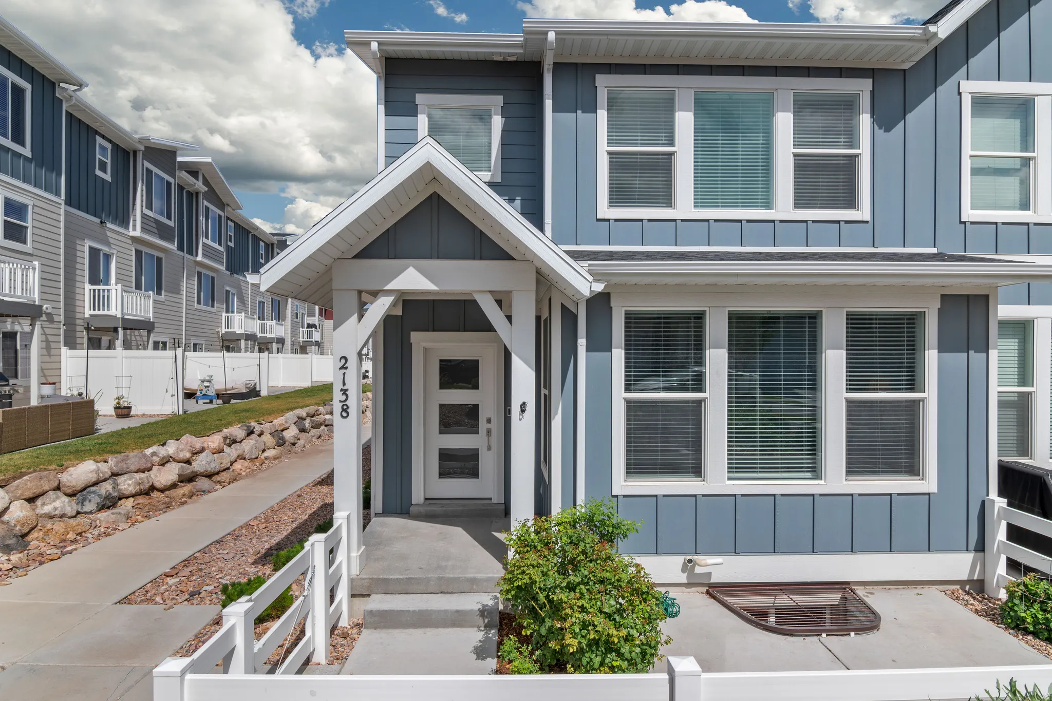 Modern townhome exterior featuring blue vertical siding and white trim