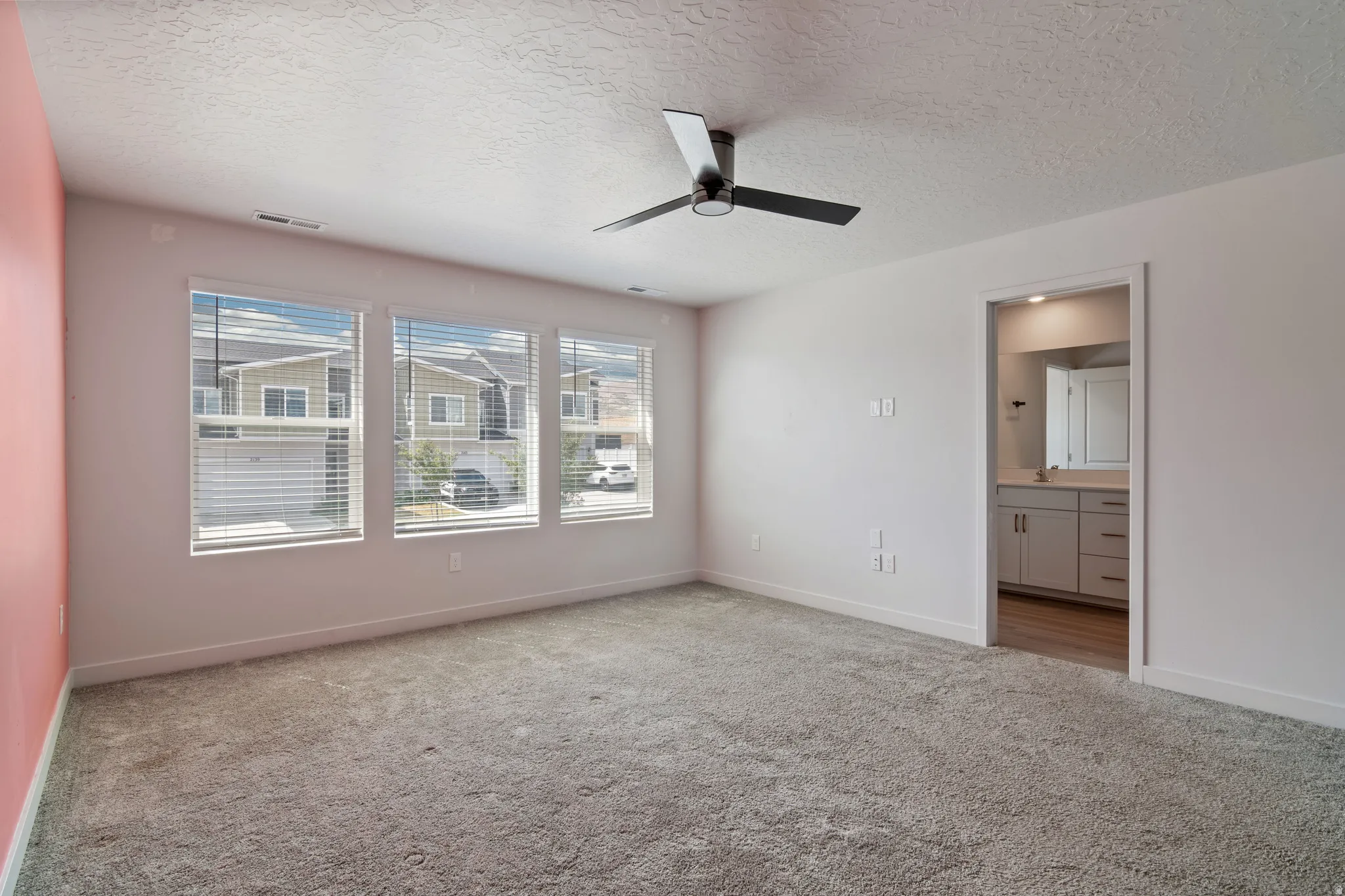 Spacious Master Bedroom featuring plush grey carpeting, white walls, and a modern ceiling fan