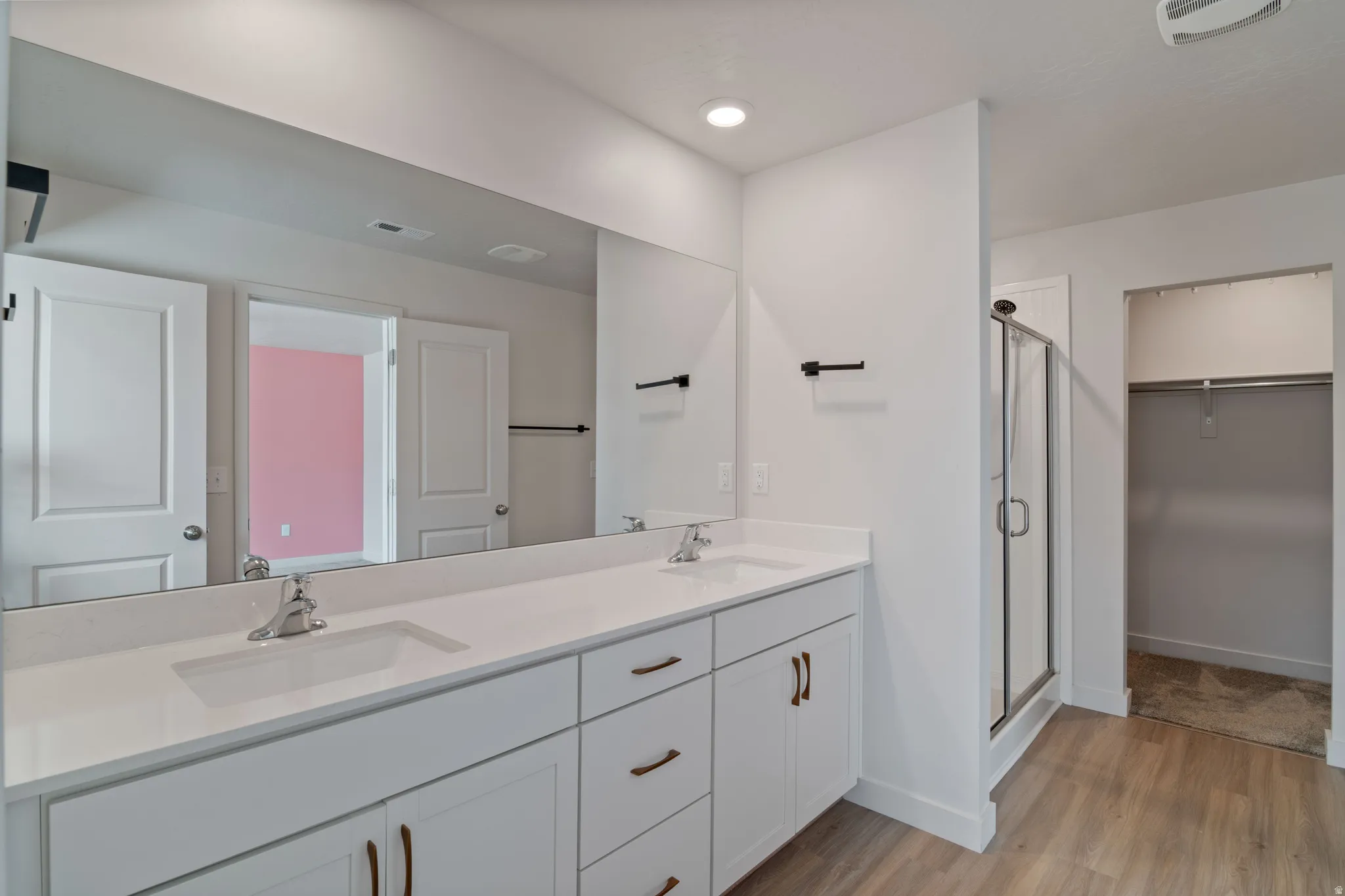 Dual master vanity with white cabinetry and integrated sinks set beneath a full-width mirror