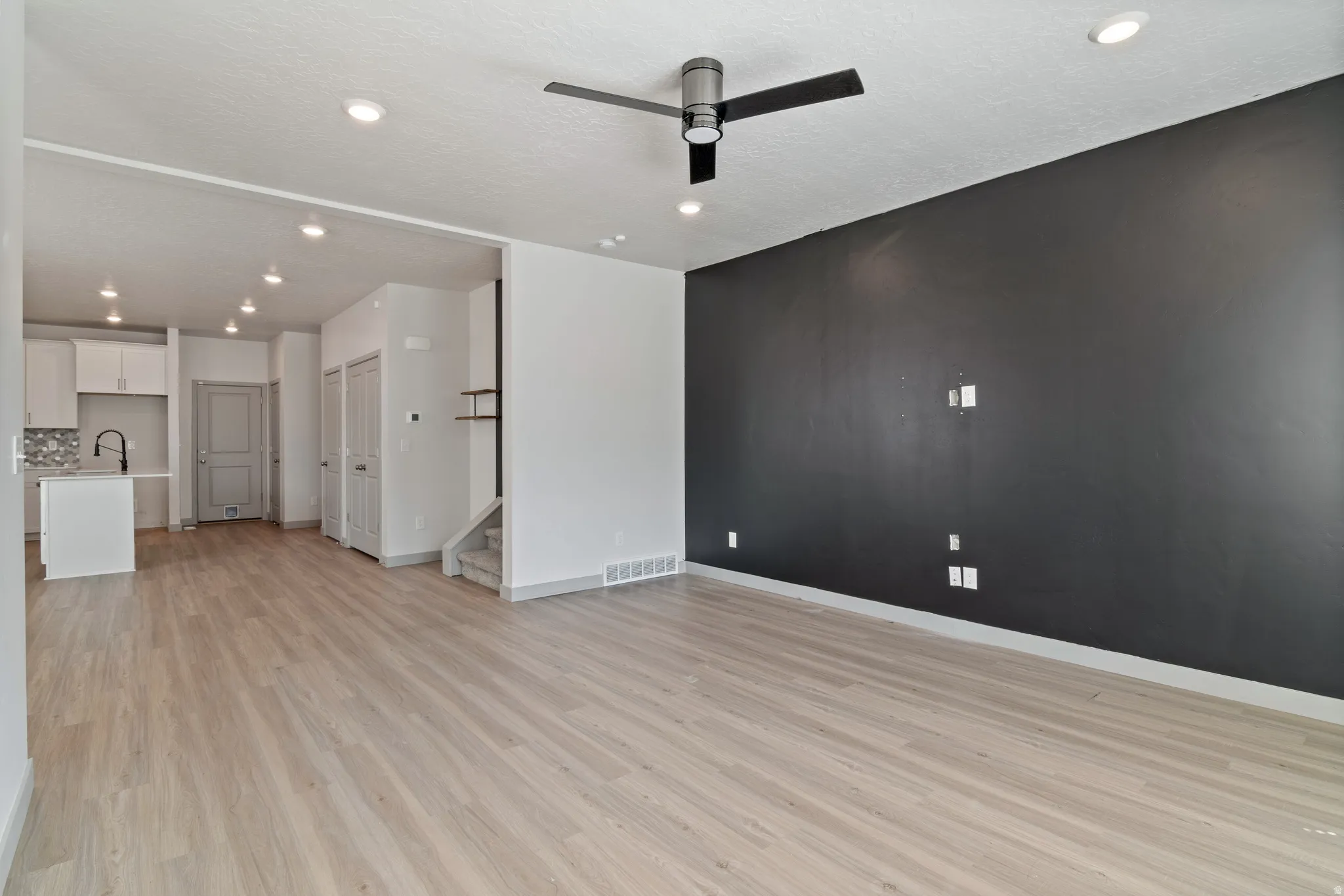 Open-concept living space featuring wood-finish flooring, recessed lighting, and a contemporary ceiling fan