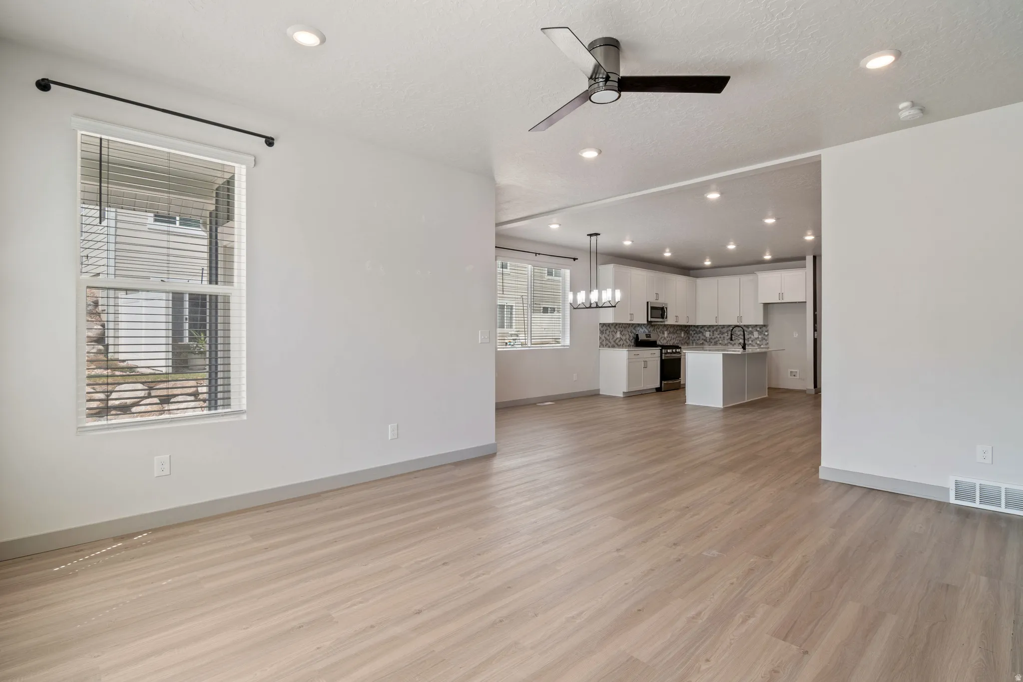 Open concept living area featuring light wood-finish flooring, a modern ceiling fan, and recessed lighting
