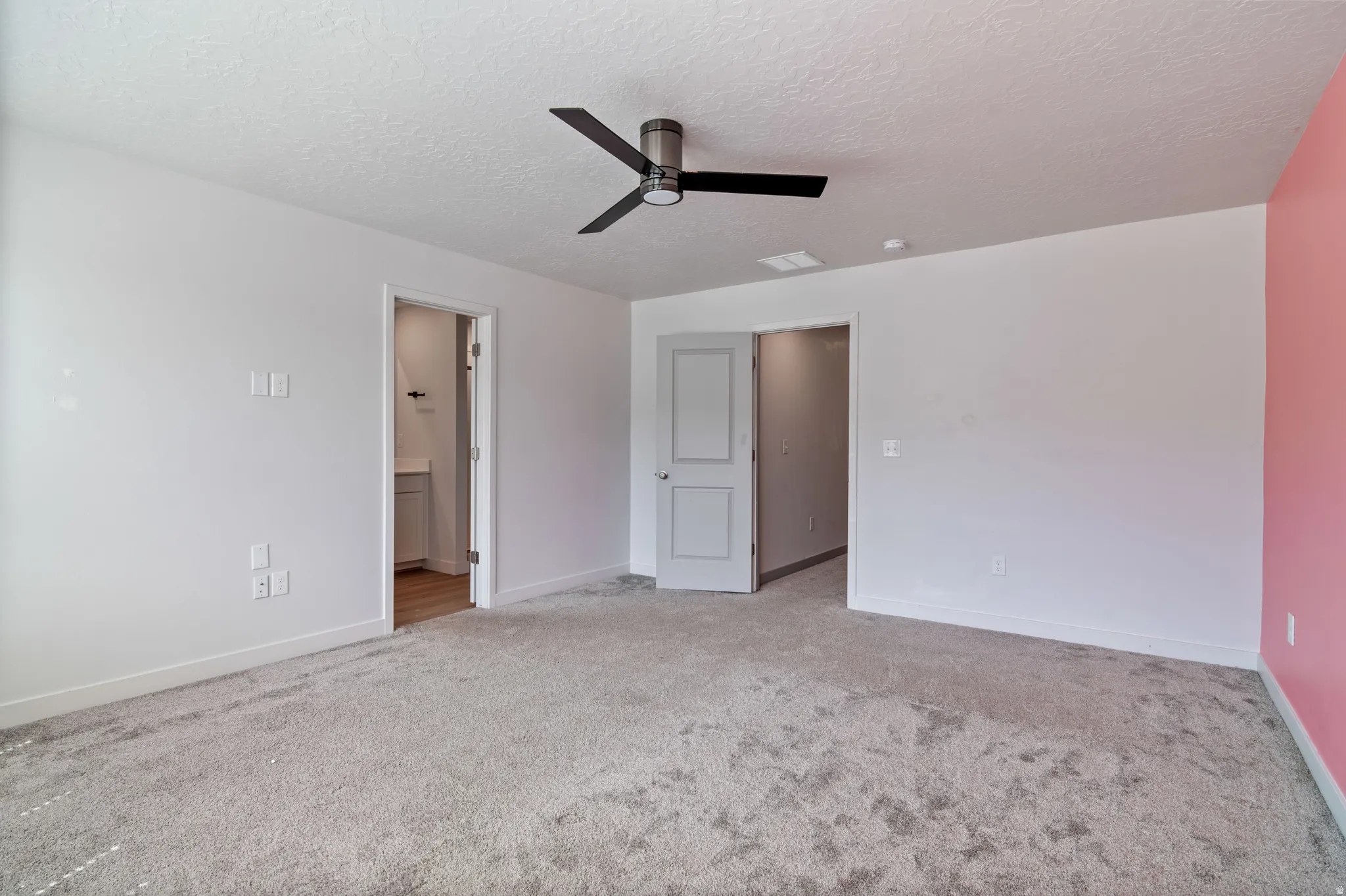 Spacious Master Bedroom featuring plush grey carpeting, white walls, and a modern ceiling fan